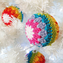 Crochet rainbow stripe bauble hanging on a Christmas tree.